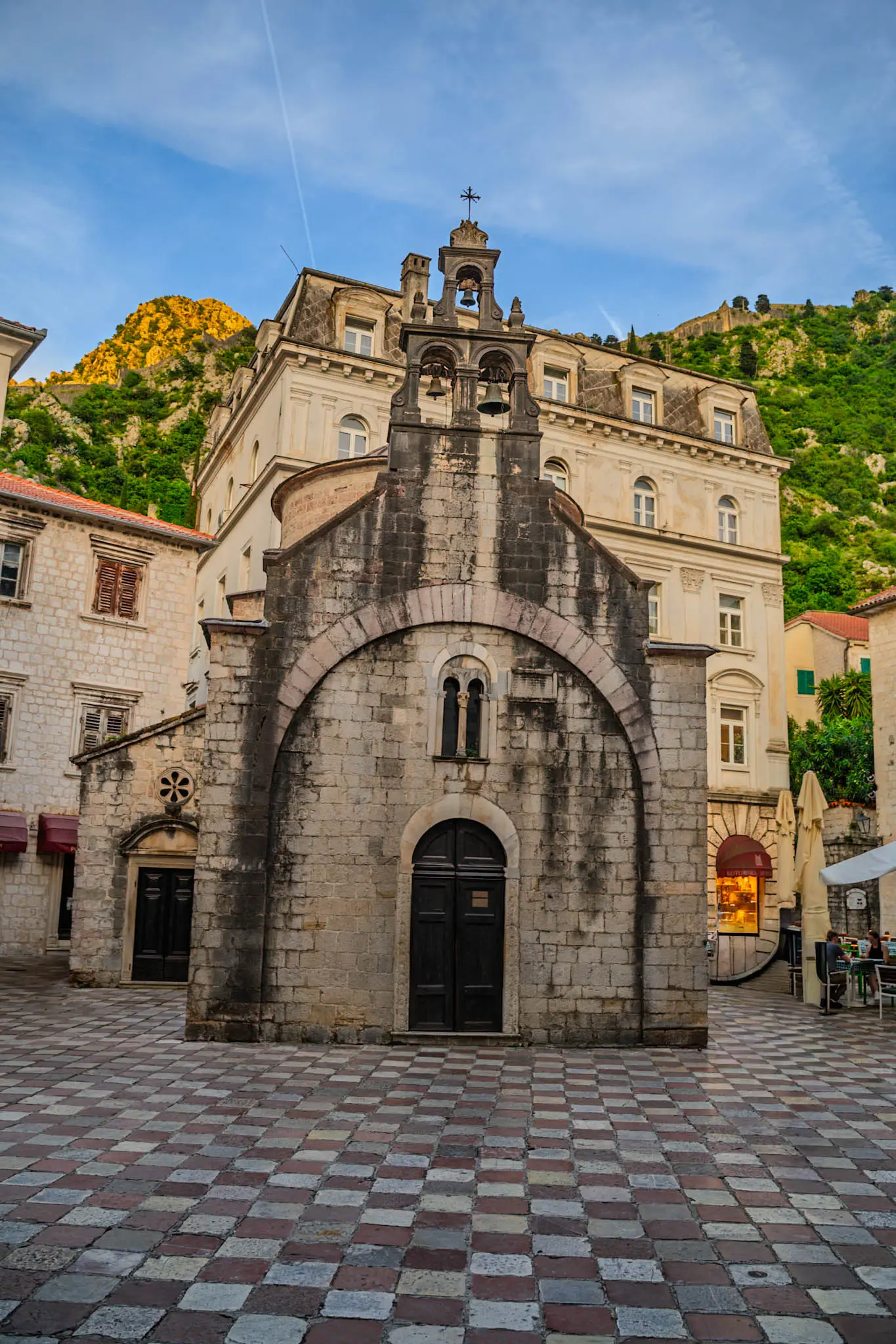 Uske kamene ulice Starog grada Kotora s mačkama koje leže na stepenicama i prolaznicima koji šetaju